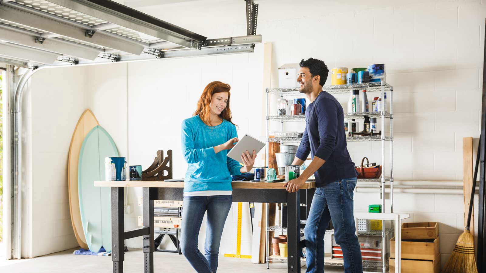 marquee-visa-direct-person-to-person-payments-1600x900 Happy man and woman talking while standing in a home garage and looking at a tablet.