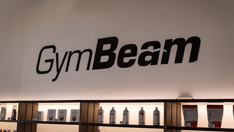 GymBeam logo on wall above shelf of products
